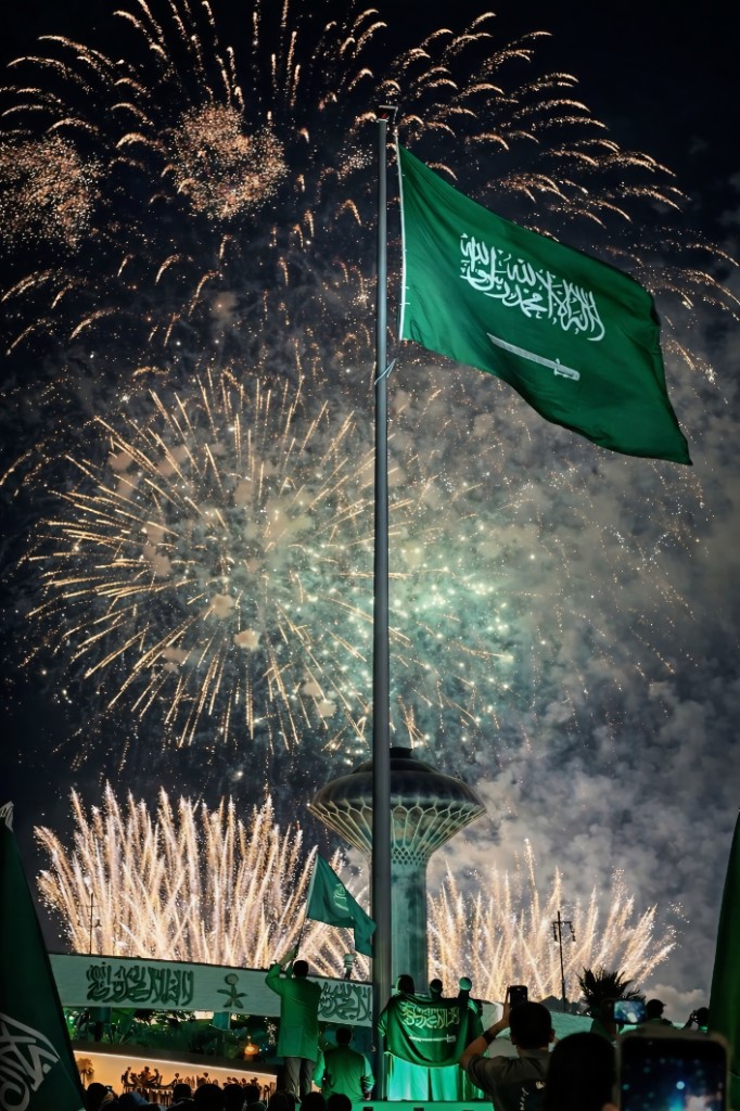 علم المملكة أمام برج المياه بالخبر مع ألعاب نارية ليلاً