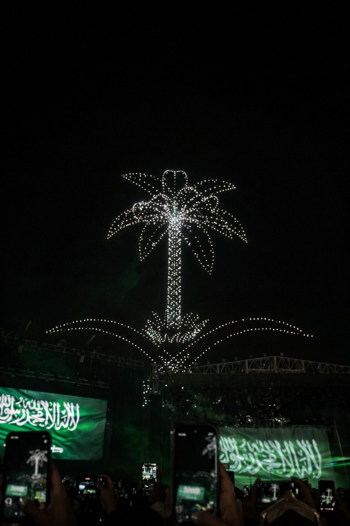 عرض طائرات درون مضيئة يشكل شعار المملكة فوق مسرح احتفالي